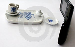 Toy tea set beside a regular flip phone