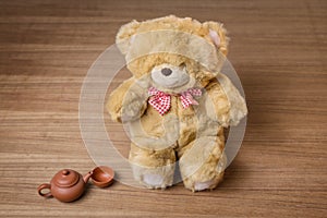 Toy teddy bear and tea kettle and cup on wooden background