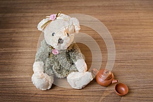 Toy teddy bear and tea kettle and cup on wooden background