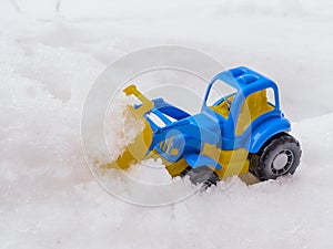 toy tractor with front loader in the snow. concept of utilities and snow removal. road services
