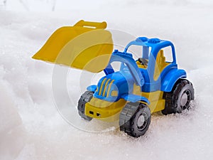 toy tractor with front loader in the snow. concept of utilities and snow removal. road services