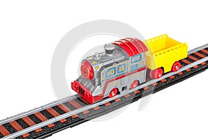 Toy train, locomotive, battery-powered steam locomotive with electric motor, trailer, car, on railway tracks, isolated on a white