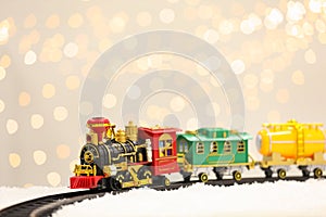 Toy train and railway on snow against Christmas lights