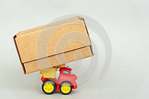 A toy truck carries a big box. The concept of freight transport, logistics, delivery of goods, trading business