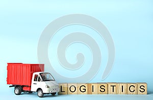 Toy truck and cubes with word LOGISTICS on blue background, space for text. Wholesale concept