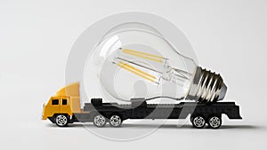 Toy truck with trailer transports modern energy-saving LED bulb. Concept of transportation services and fast delivery of