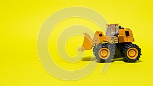 Toy typewriter tractor bulldozer on a yellow background. Toy for children