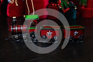 Toy vintage steam locomotive on floor under a decorated Christmas tree and gifts. Xmas toy train on Christmas tree background. Chr