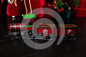 Toy vintage steam locomotive on floor under a decorated Christmas tree and gifts. Xmas toy train on Christmas tree background. Chr