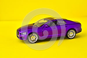 Toy violet model of car on yellow background