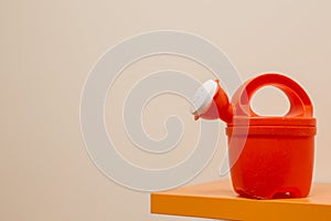 Toy watering can on orange shelf