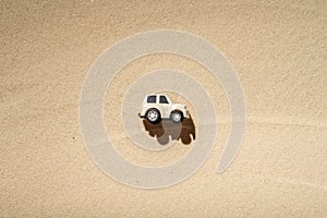 Toy white safari jeep on the sands of the beach, desert dunes. Concept.