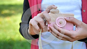 Toy wooden camera in the hands of a teenage girl.