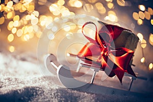 Toy wooden sledge with gift standing in snow. Christmas