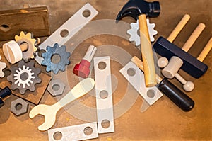 Toy wooden toy tools including gears and a wrench and hammer scattered on a wooden surface - top lay