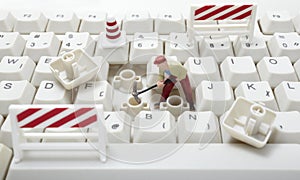 Toy workers repairing computer keyboard