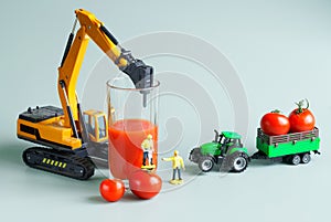 Toy workers use construction machinery to squeeze juice from fresh red tomatoes. The concept of making tomato juice. Toy world