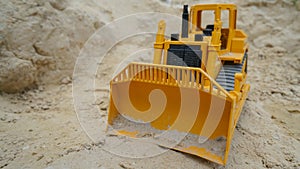 A toy yellow bulldozer digs the sand.