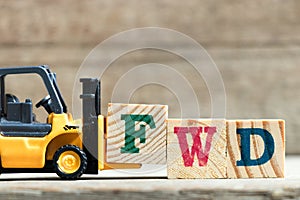 Toy yellow forklift hold letter block F to complete word FWD & x28;Abbreviation of forward& x29; photo