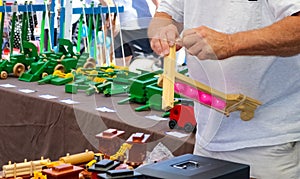 Toymakers hands putting together a wooden toy in a booth at out outside festival