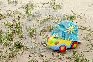 Toys car, from above a children`s hat on the sand among the gras