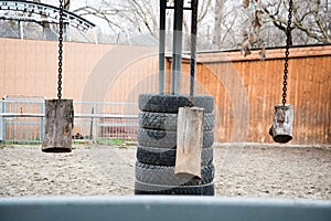 Toys for entertaining animals in the zoo. Logs hung on chains for hoofed animals. Tires and logs for bison