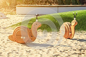 toys of rocking chair in form of snails on modern playground with covering from sand