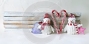 Toys snowmen, caramel sticks, Christmas decorations on a light wooden background