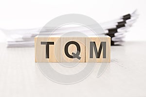 TQM letters on wooden cubes. the background is a white business papers. finance concept