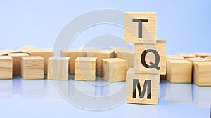 TQM. wooden cubes. blocks lie on a black background. stacks with coins. inscription on the cubes is reflected from the