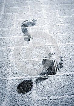 Traces of bare feet on snowy pavement