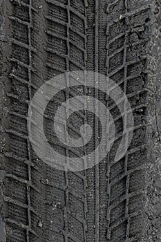 Traces of car tire tread in the ground. Pattern. Dark abstract background. Imprint of wheels. Textured soil. Drawing