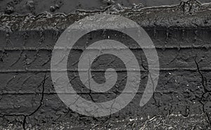 Traces of car tire tread in the ground. Pattern. Dark abstract background. Imprint of wheels. Textured soil. Drawing