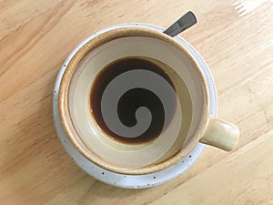 Traces or empty of hot black coffee in brown ceramic cup and white saucer on wooden table