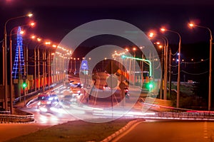 Traces of headlights from cars moving at night on the bridge, illuminated by lanterns. Abstract city landscape with highway