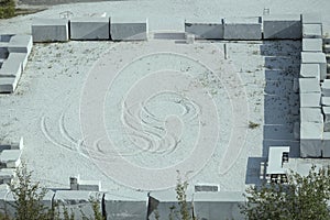 Traces on marble powder among carved marble blocks ready for spedition, Carrara, Italy