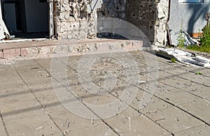 Traces on paving slabs from a shell hit. Part of the building destroyed by the shock wave and shrapnel. photo