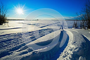 Traces of snowmobiles on the snow in field .