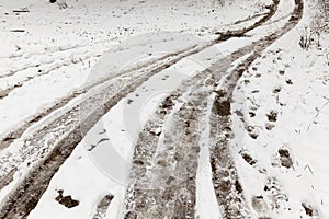 Traces of the wheels of the car on a rural road covered with snow