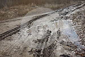 Track from car tire in dirt road in spring. Traces of stuck vehicles in liquid mud. Danger to driving