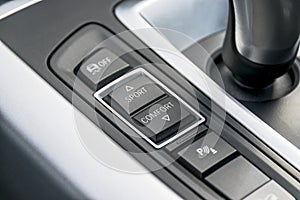 Track control buttons near automatic gear stick of a modern car, car interior details.