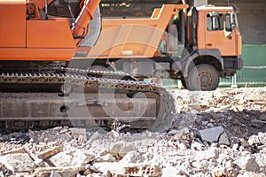 Track excavator and dump truck over loads of rubble debris