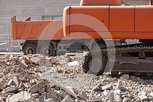 Track excavator and dump truck over loads of rubble debris