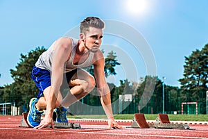 Track and field sprinter on starting point at cinder track in sp