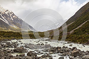 The track among green valley in the Southern Alps in the lake Mueller. A river among the hills. South Island, New Zealand.