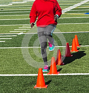 Track runner performing speed drill over orange cones