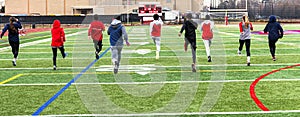 Track runners doing warm up running drills on turf field