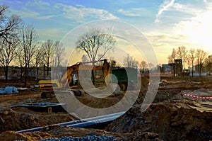 Tracked excavator with a bucket in the ground at a construction site during the laying of sewer pipes in the ground