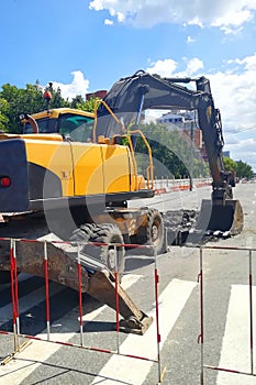 Tracked excavator on the street asphalt road repair.