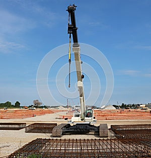 Tracked mobile telescopic crane in a large construction site, with steel cages in front